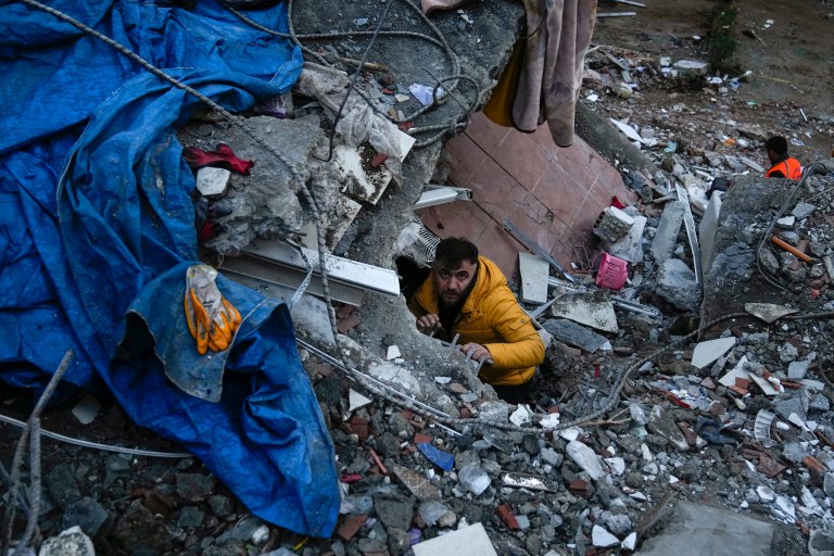 A man searches for people in a destroyed building in Adana, Turkey, Monday, Feb. 6, 2023. A powerful quake has knocked down multiple buildings in southeast Turkey and Syria and many casualties are feared.
