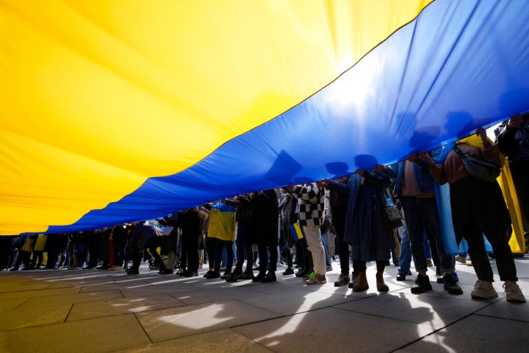 People hold a giant Ukrainian flag during a rally to mark the one-year anniversary of Russia's invasion of Ukraine in Belgrade, Serbia, Friday, Feb. 24, 2023. A traditional Slavic ally, Serbia has maintained friendly relations with Russia despite the invasion and has refused to join Western sanctions designed to punish Moscow for the aggression. 