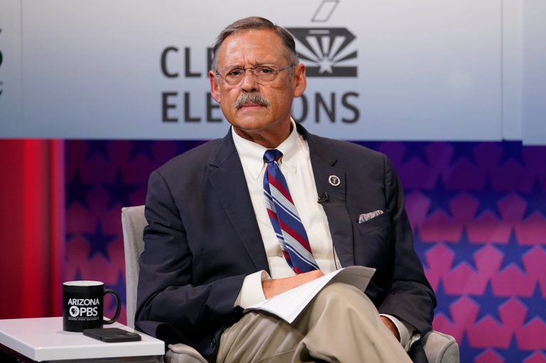 Arizona Secretary of State Republican candidate Mark Finchem listens to instructions prior to debating democratic challenger Adrian Fontes, Sept. 22, 2022, in Phoenix. 