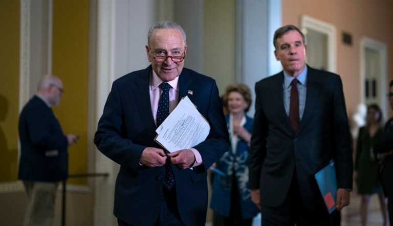 Senate Majority Leader Chuck Schumer, D-N.Y., joined by Sen. Mark Warner, D-Va., chair of the Senate Intelligence Committee, right.