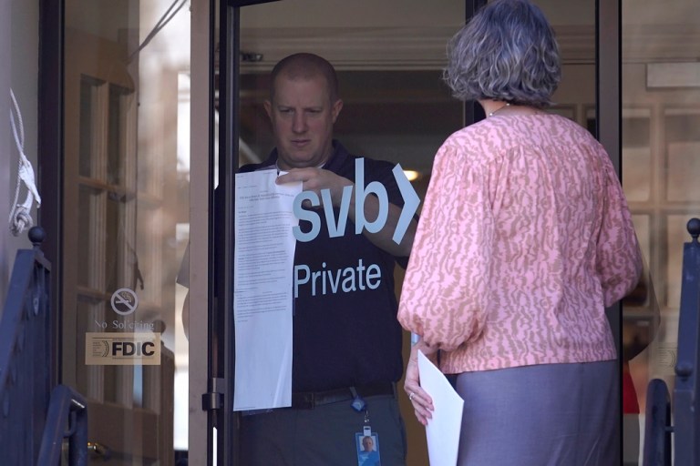 A person removes a paper notice from a glass door at the Silicon Valley Bank branch location, in Wellesley, Mass., Monday, March 27, 2023. North Carolina-based First Citizens will buy Silicon Valley Bank, the tech industry-focused financial institution that collapsed earlier this month. 