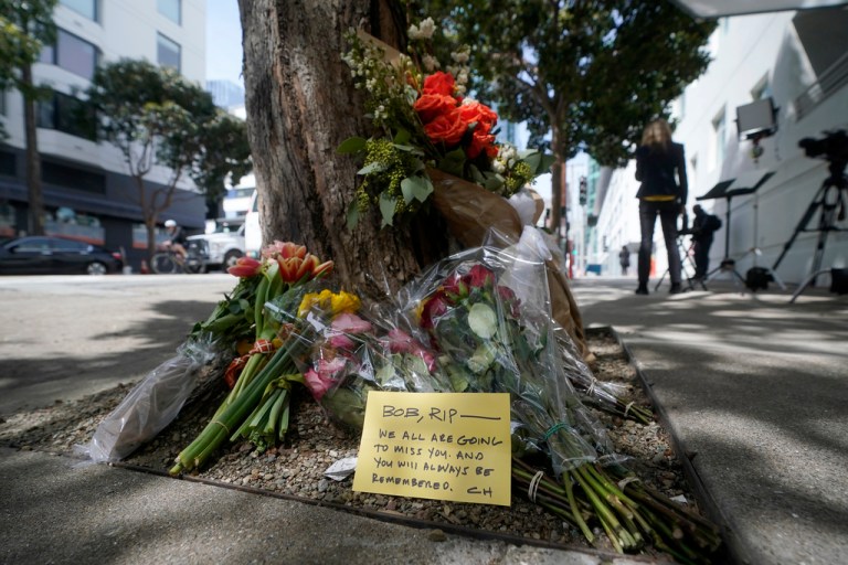 Flowers sit at a tree in front of the building where a technology executive was fatally stabbed.