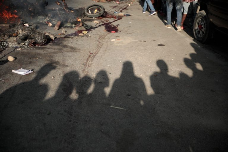 Bystanders gather around the bodies of alleged gang members that were set on fire by a mob after they were stopped by police while traveling in a vehicle in the Canape Vert area of Port-au-Prince, Haiti, Monday, April 24, 2023. 
