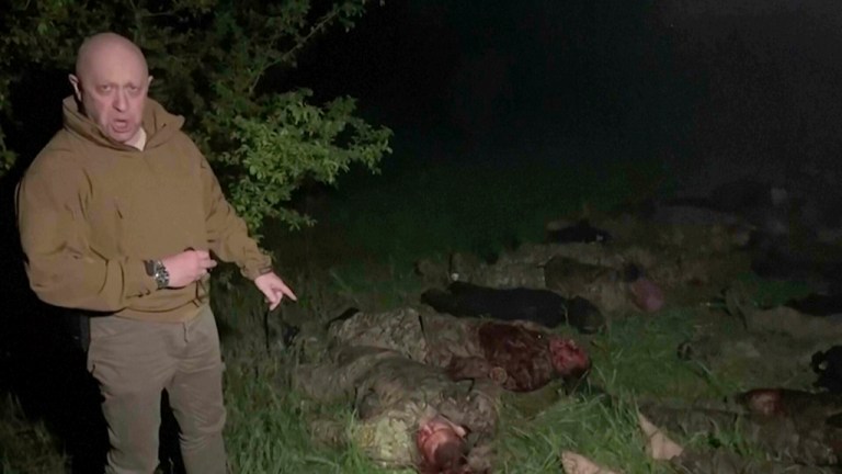 In this handout image taken from a video released by Prigozhin Press Service on Friday, May 5, 2023, head of Wagner Group Yevgeny Prigozhin stands in front of multiple bodies lying on the ground in an unknown location. 