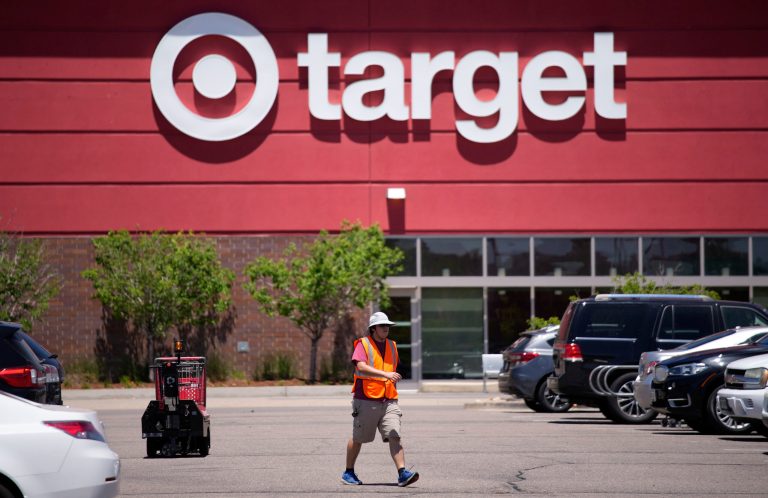 A worker collects shopping carts in the parking lot of a Target store on June 9, 2021, in Highlands Ranch, Colorado.