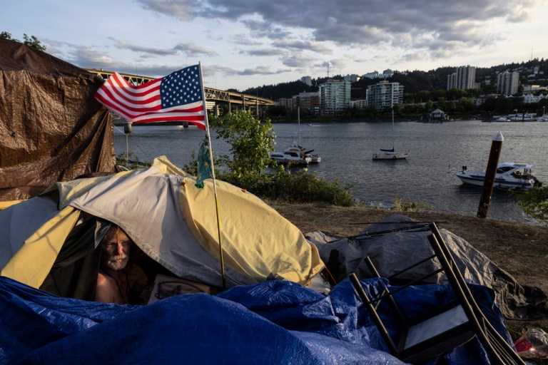 Frank, a homeless man, sits in his tent with a river view in Portland, Oregon, on June 5, 2021.