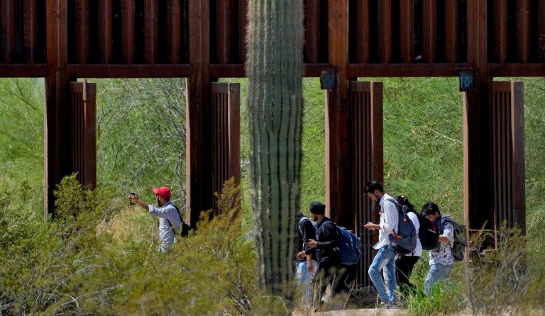 A group claiming to be from India walk past open border wall storm gates after crossing through the border fence in the Tucson Sector of the U.S.-Mexico border, Tuesday, Aug. 29, 2023, in Organ Pipe Cactus National Monument near Lukeville, Arizona.