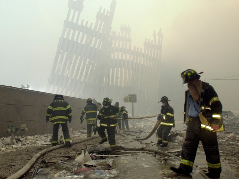 FILE - Firefighters work beneath the destroyed mullions, the vertical struts which once faced the soaring outer walls of the World Trade Center towers, after a terrorist attack in New York, Sept. 11, 2001. (AP Photo/Mark Lennihan, File)