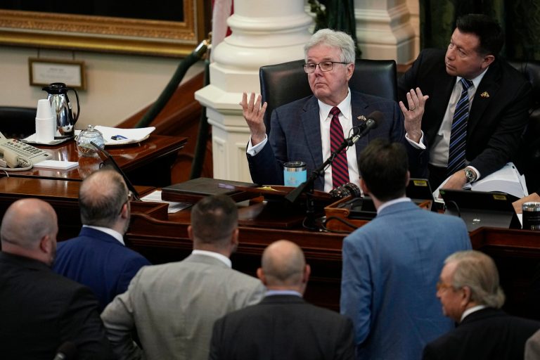 Texas Lt. Gov. Dan Patrick, center, throws up his hands as he talks with defense and prosecution attorneys during the impeachment trial for Texas Attorney General Ken Paxton in the Senate Chamber at the Texas Capitol, Wednesday, Sept. 13, 2023, in Austin, Texas. 