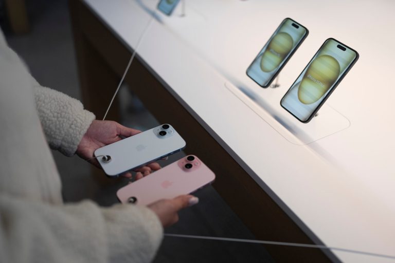 A shopper compares two iPhone 15 models on the first day of sales at an Apple Store in Los Angeles, Friday, Sept. 22, 2023.
