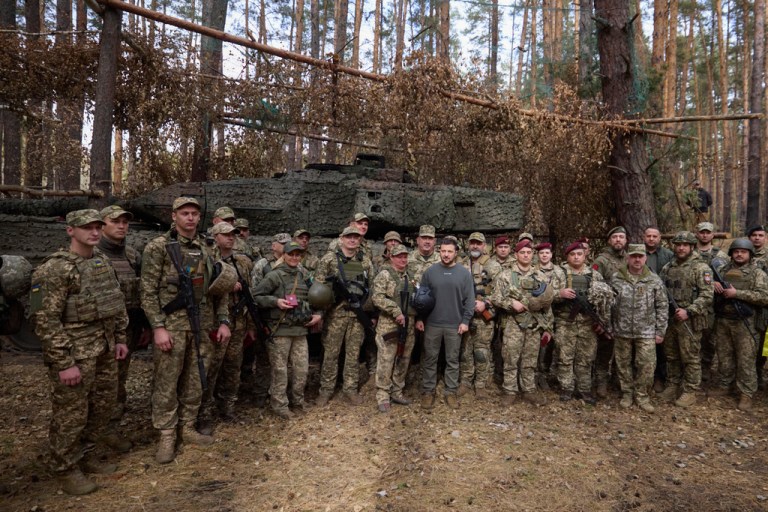 In this photo provided by the Ukrainian Presidential Press Office, Ukrainian President Volodymyr Zelensky, center, poses for a photo with the Ukrainian soldiers in front of a Leopard 2 tank on the front line in the Kharkiv region, Ukraine, Tuesday, Oct. 3, 2023.