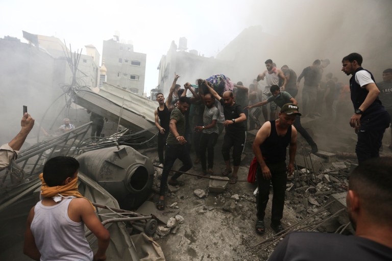 Palestinians remove a dead body from the rubble of a building after an Israeli airstrike in the Gaza Strip on Monday, Oct. 9, 2023. 