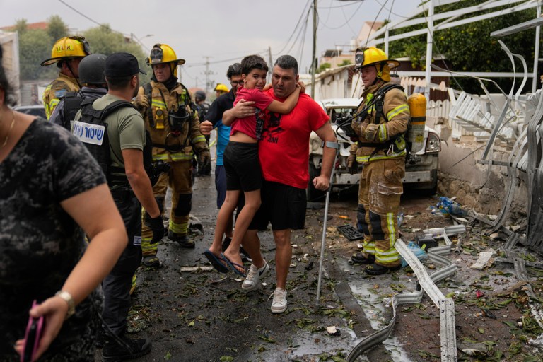 Israelis evacuate a site struck by a rocket fired from the Gaza Strip, in Ashkelon, southern Israel, Monday, Oct. 9, 2023.