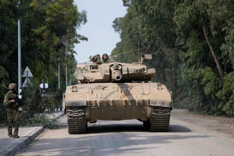 An Israeli army tank drives in kibbutz Kfar Azza on Tuesday, Oct. 10, 2023.