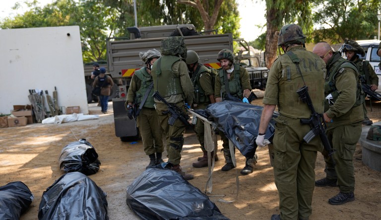 Israeli soldiers carry the body of a person killed by Hamas militants in Kibbutz Kfar Azza on Tuesday, Oct. 10, 2023. Hamas militants overran Kfar Azza on Saturday, where many Israelis were killed and taken captive.