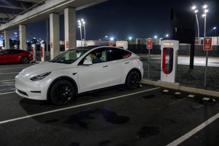 A driver charges a Tesla vehicle at a charging station in a shopping mall parking lot in East Rutherford, New Jersey, on Saturday, Oct. 7, 2023. 