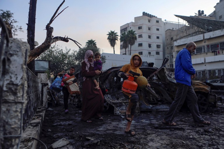 Palestinians carry belongings as they leave al Ahli hospital, which they were using as a shelter, in Gaza City, Wednesday, Oct. 18, 2023.