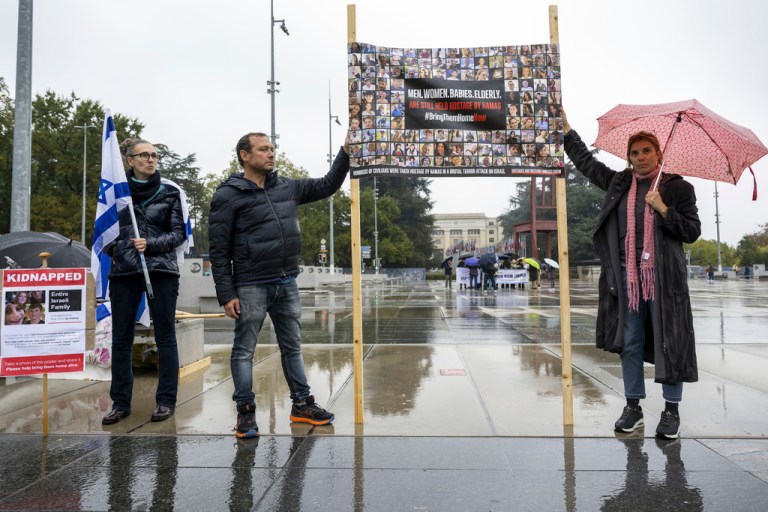 Protesters hold banners with hostages' pictures during a gathering next to the European headquarters of the United Nations in Geneva, Switzerland, Thursday, Oct. 19, 2023.