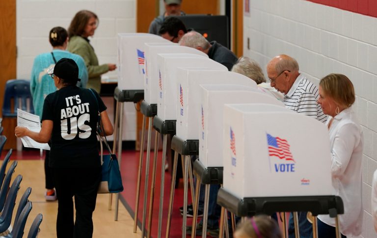 A voter, left, carries her ballot to the counting machine after voting at a polling station on Tuesday, Nov. 7, 2023, in Richmond, Virginia.