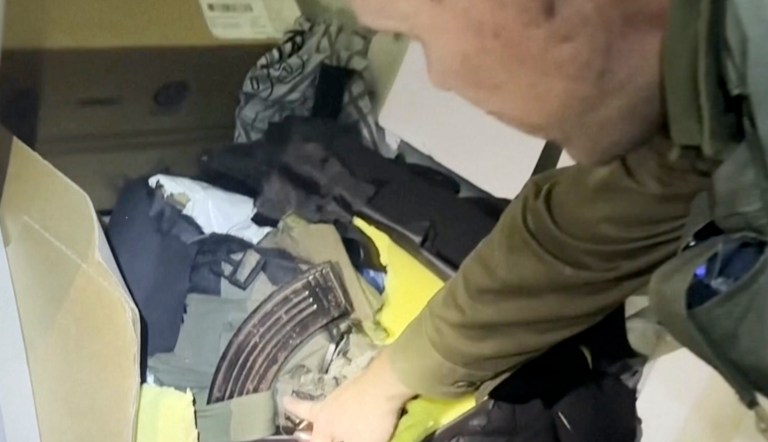 In this image taken from a video released by the Israel Defense Forces, Wednesday, Nov. 15, 2023, Lt. Col. Jonathan Conricus, an Israeli military spokesman, points to a cache of weapons the IDF says were found in an MRI center at the Shifa hospital in Gaza City.