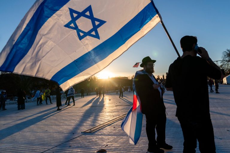 Menachem Roetter of Detroit, left, walks behind an Israeli flag at the end of the 