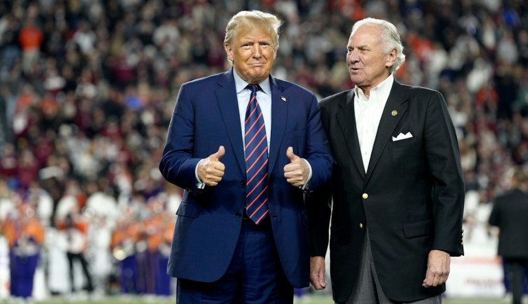 Former President Donald Trump, left, gestures with Gov. Henry McMaster (R-SC) during halftime in an NCAA college football game between the University of South Carolina and Clemson University on Saturday, Nov. 25, 2023, in Columbia, South Carolina.