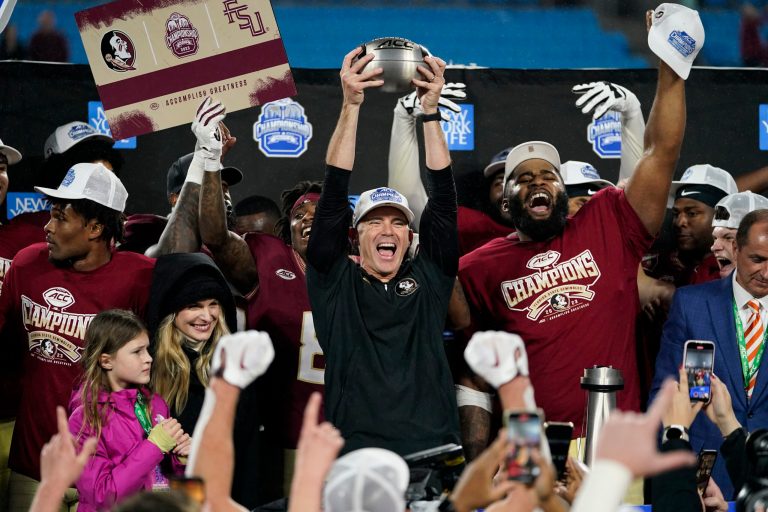 Florida State coach Mike Norvell lifts the trophy after the team's win over Louisville in the Atlantic Coast Conference championship NCAA college football game, Saturday, Dec. 2, 2023, in Charlotte, North Carolina.
