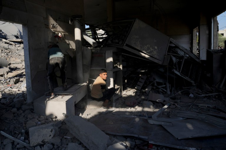 Palestinian children salvage belongings from a house destroyed in the Israeli bombardment of the Gaza Strip in Deir al Balah on Monday, Dec. 4, 2023.