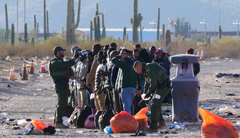 Members of the U.S. Border Patrol and U.S. Customs and Border Protection organize a group of immigrants as hundreds of immigrants gather along the border Tuesday, Dec. 5, 2023, in Lukeville, Arizona.