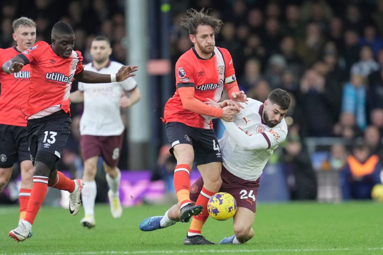 Luton Town's Tom Lockyer, center, and Manchester City's Josko Gvardiol, right, vie for the ball during an English Premier League soccer match on Sunday, Dec. 10, 2023, at Kenilworth Road stadium in Luton, England.