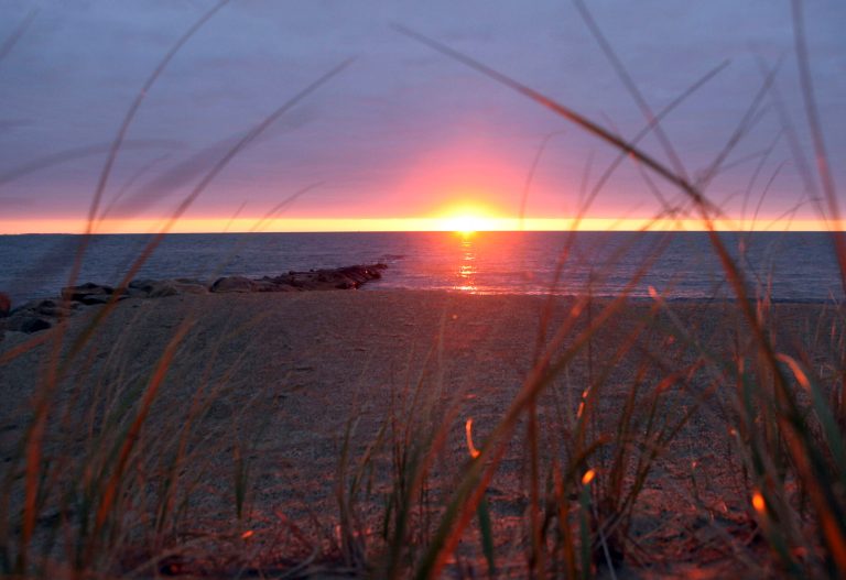 FILE - In this Oct. 30, 2009 file photo, the sun begins to rise over Nantucket Sound as seen from Popponesset Beach in Mashpee, Mass., where the Cape Wind off-shore wind turbine power generation project won approval for construction. The project faces benchmarks, including one that stipulates construction must begin by Dec. 31, 2013, or proof the developers have incurred tens of millions of dollars in costs by then.  