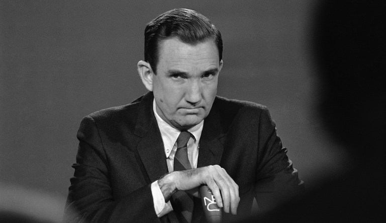 A grim-faced Attorney General Ramsey Clark covers the microphone on April 7, 1968 during an appearance on television from Washington.    He said that federal investigators are on the trail of "one man on the run"  in the assassination of  Dr. Martin Luther King, Jr., and hope for an early arrest.   Clark was a guest on the program "Meet the Press,"  aired by the National Broadcasting Company.