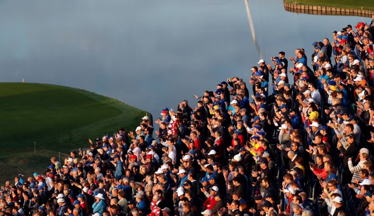 Supporters watch players while standing in a grandstand overlooking the first tee on the opening day of the 2018 Ryder Cup at Le Golf National in Saint-Quentin-en-Yvelines, France, Friday, Sept. 28, 2018.