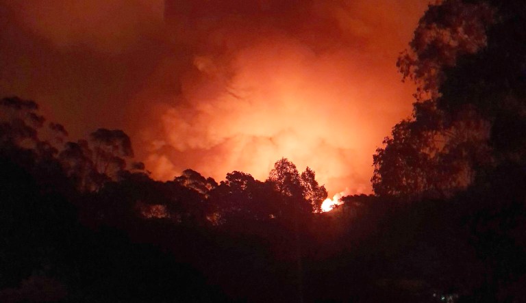 In this Dec. 31, 2019, photo provided by Siobhan Threlfall, a fire approaches the village of Nerrigundah, Australia.