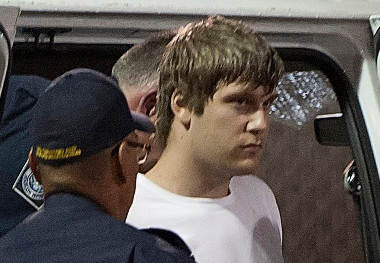   Travis Baumgartner is taken out of a van by Canadian Border Services officers at the Aldergrove, British Columbia border crossing, Saturday, June 16, 2012. Baumgartner was stopped by customs at the United States border as he tried to enter the U.S. Baumgartner is wanted in a deadly armored car heist at a university in western Canada that left three armed guards dead, Friday. (AP Photo/Jonathan Hayward, The Canadian Press)  