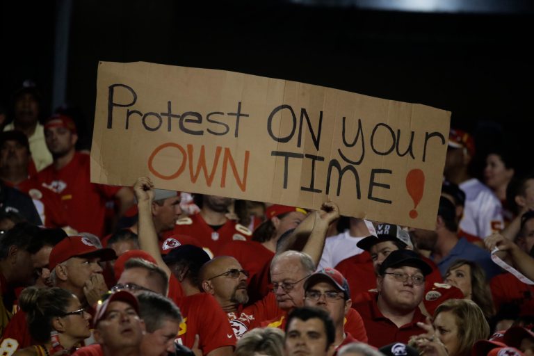A Kansas City Chiefs fan holds a sign against the anthem protests during the first half of an NFL football game against the Washington Redskins in Kansas City, Mo., Monday, Oct. 2, 2017. (AP Photo/Charlie Riedel)