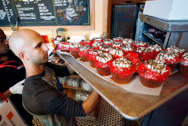 FILE - In this Sept. 20, 2007 file photo, Crumbs Bake Shop managing partner Harley Bauer carries of tray of cupcakes during the store's grand opening in Beverly Hills, Calif. Crumbs on Monday, July 7, 2014 said it is shuttering all its stores, a week after the struggling cupcake shop operator was delisted from the Nasdaq. (AP Photo/Matt Sayles, File)