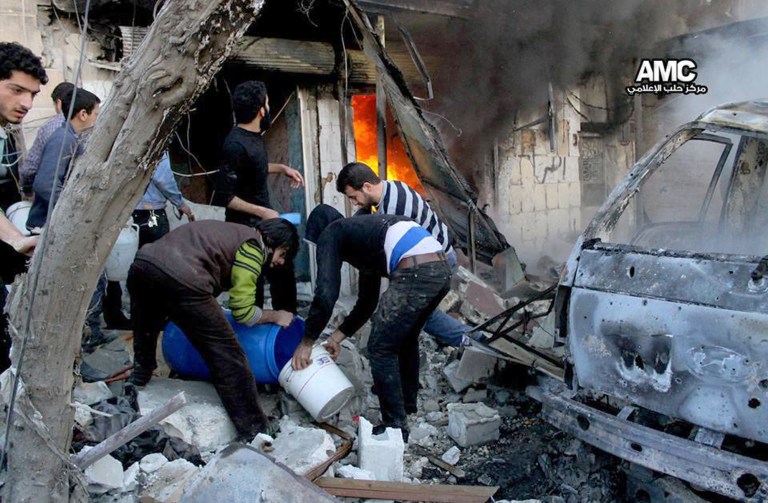 In this citizen journalism image provided by Aleppo Media Center (AMC), an anti-Bashar Assad activist group, and authenticated based on its contents and other AP reporting, Syrian citizens fill water in a bucket to extinguish shops in flames caused by a Syrian government forces warplane attack, at al-Bab neighborhood in Aleppo, Syria, Saturday, Feb. 1, 2014. Syrian military helicopters dropped barrels packed with explosives on rebel-held areas of the northern city of Aleppo on Saturday, killing at least a dozen of people including a family trapped in a car, as government forces inched closer to opposition-held areas. (AP Photo/Aleppo Media Center, AMC)