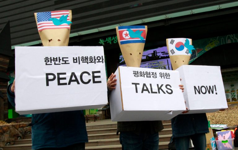 South Korean protesters wearing masks made out of envelopes displaying the flags of the United States, left, North Korea, center, and South Korea, right, participate in a rally to mark Global Day of Action on Military Spending near the U.S. Embassy in Seoul, South Korea, Monday, April 15, 2013. The protesters demanded a peaceful unification of the Korean peninsula. (AP Photo/Ahn Young-joon)