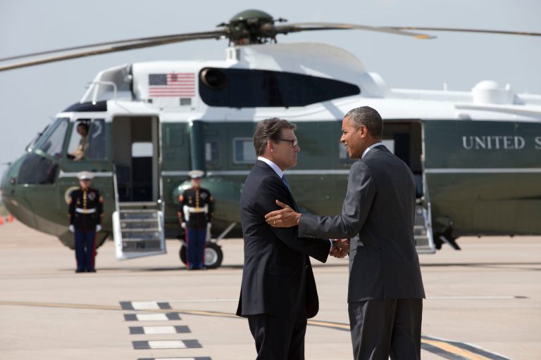 President Barack Obama is greeted by Texas Gov. Rick Perry as he arrives at Dallas/Fort Worth International Airport, Wednesday, July 9, 2014. The president is expected to attend a meeting on immigration, (AP Photo/Jacquelyn Martin)