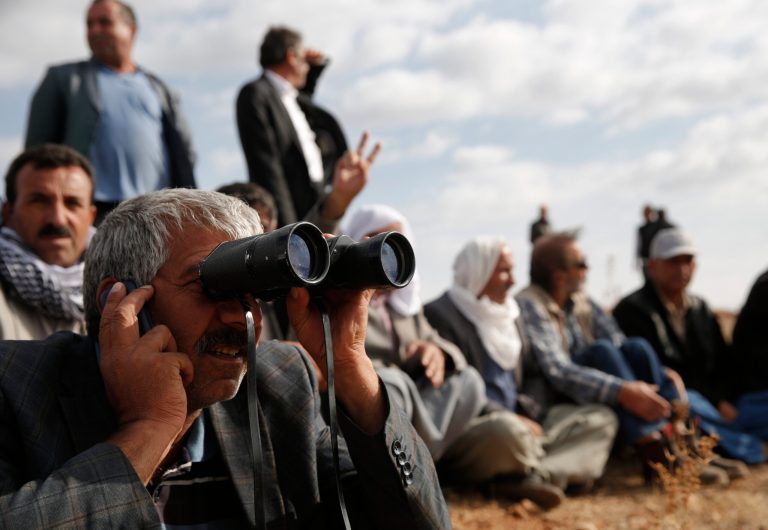 People gather on a hilltop on the outskirts of Suruc, at the Turkey-Syria border, to watch fighting between Syrian Kurds and the militants of Islamic State group in Kobani, Syria, over the border, Wednesday, Oct. 15, 2014. Kobani, also known as Ayn Arab, and its surrounding areas, has been under assault by extremists of the Islamic State group since mid-September and is being defended by Kurdish fighters. (AP Photo/Lefteris Pitarakis)