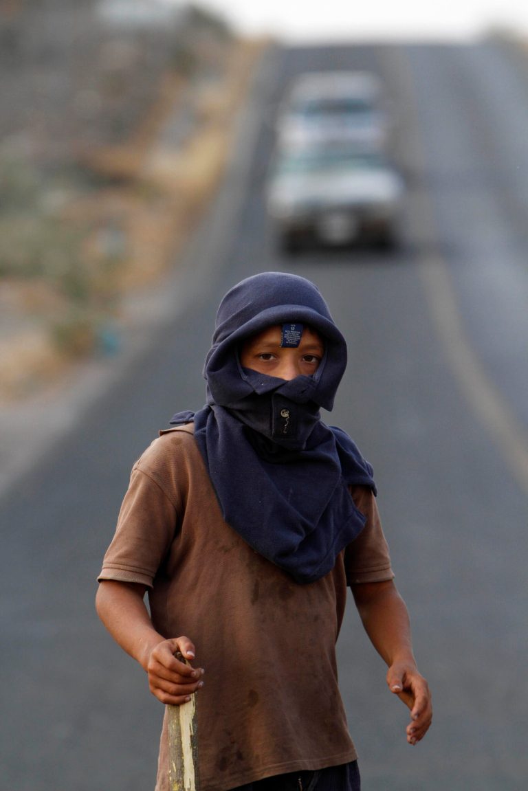 In this May 20, 2013 photo, a masked youth stands guard at the entrance of the town of Buenavista, Mexico. Self-defense groups started to spring up in February to fight back the Knights Templar drug cartel which is extorting protection payments from cattlemen and lime growers, butchers and even marijuana growers. The federal government sees both the self-defense forces and the cartel as dangerous enemies. (AP Photo/Marco Ugarte)