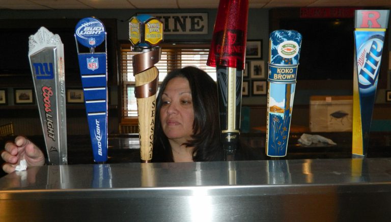 In this March 31, 2014 photo, Gigi Liaguno-Dorr polishes the beer taps at Jakeabob's, the Union Beach N.J. restaurant she used to operate until having to close it the previous weekend. The original Jakeabob's was destroyed in Supoerstorm Sandy, and she moved the  business a few blocks inland for 2013. But a continuing inability to get timely rebuilding aid forced her to close the restaurant for good on March 28. The reopening of Jakeabob 's was seen as an inspiration to the still-struggling Raritan Bay community. (AP Photo/Wayne Parry)