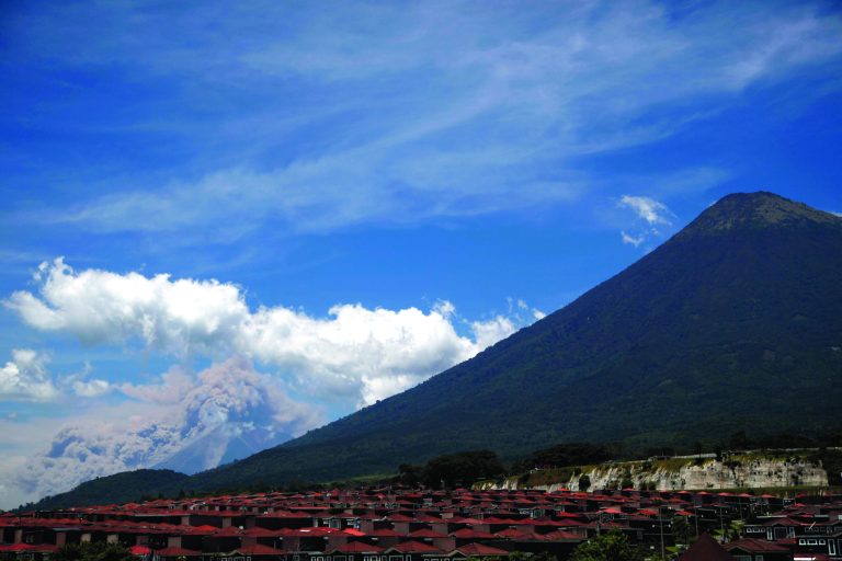 Volcanic ash spews from the Volcan de Fuego or Volcano of Fire, left, as seen from Palin, south of Guatemala City, Thursday, Sept. 13, 2012. The long-simmering volcano exploded into a series of powerful eruptions Thursday, hurling thick clouds of ash nearly two miles (three kilometers) high, spewing rivers of lava down its flanks and forcing the evacuation of more than 33,000 people from surrounding communities. (AP Photo/Moises Castillo)