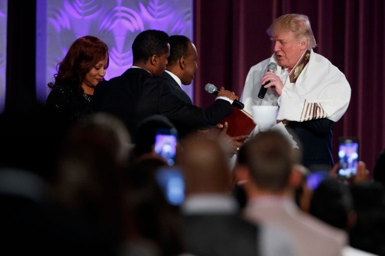 Republican presidential candidate Donald Trump wears a prayer shawl as he is presented with a gift during a church service at Great Faith Ministries, Saturday, Sept. 3, 2016, in Detroit. (AP Photo/Evan Vucci)