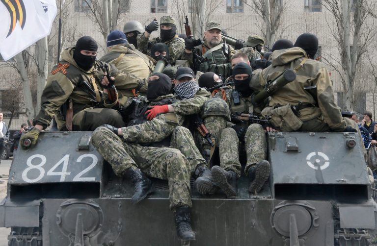 A combat vehicle with pro-Russian gunman on top runs through downtown Slovyansk on Wednesday, April 16, 2014. The troops on those vehicles wore green camouflage uniforms, had automatic weapons and grenade launchers and at least one had the St. George ribbon attached to his uniform, which has become a symbol of the pro-Russian insurgency in eastern Ukraine. (AP Photo/Efrem Lukatsky)
