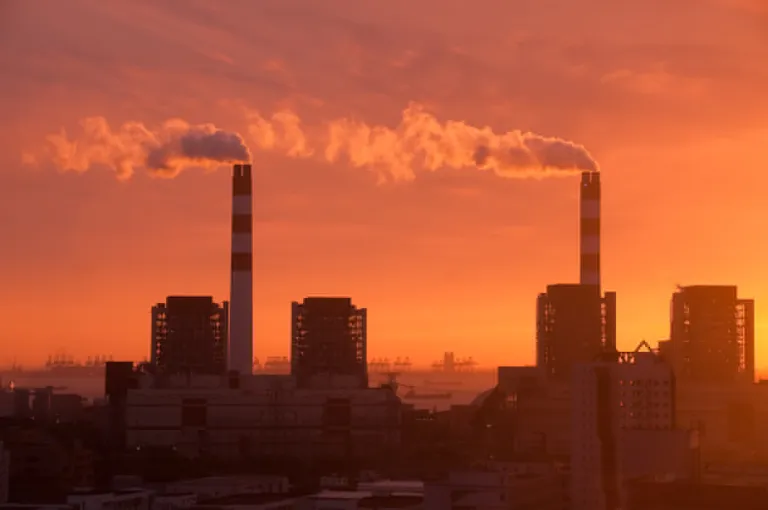 Smoke stacks and buildings at sunset.