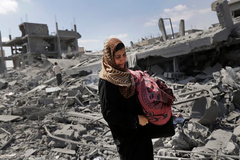 A Palestinian woman carries her belongings past the rubble of houses destroyed by Israeli strikes in Beit Hanoun, northern Gaza Strip, Saturday, July 26, 2014. Thousands of Gaza residents who had fled Israel-Hamas fighting streamed back to devastated border areas during a lull Saturday, and were met by large-scale destruction: scores of homes were pulverized, wreckage blocked roads and power cables dangled in the streets. (AP Photo/Lefteris Pitarakis)