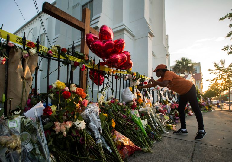 A mourner places flowers along the fence outside the Emanuel AME Church, Saturday, June 20, 2015 in Charleston, S.C. (AP Photo/Stephen B. Morton)
