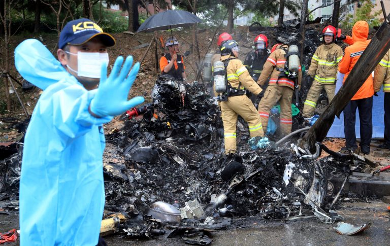 Firefighters inspect the wreckage of a helicopter which crashed near an apartment complex and school in Gwangju, South Korea, Thursday, July 17, 2014. The firefighting helicopter crashed Thursday, killing two people, officials said. (AP Photo/Yonhap, Park Chul-hong) KOREA OUT